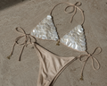 Bikini set with shell-like top and beige bottom on sand